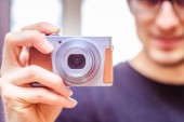 Mladý muž s vintage camera usměje a pořídí fotografii