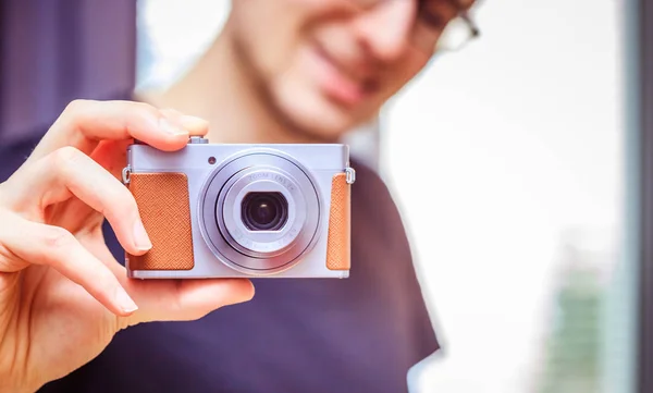 Young man with vintage camera smiles and takes a photo