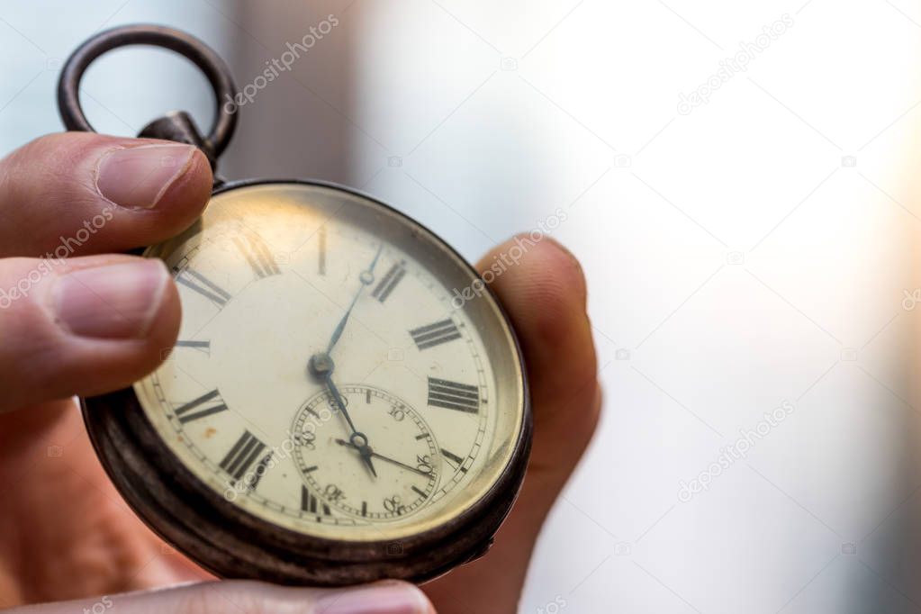 Time goes by: Man is holding a vintage watch in his hand, busine