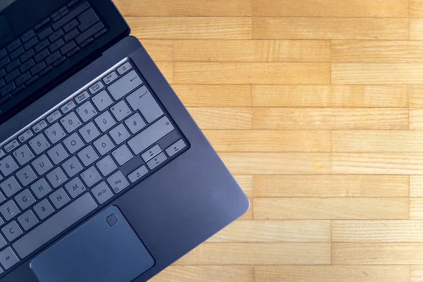 Cutout of a modern laptop keyboard on the wooden floor with text space