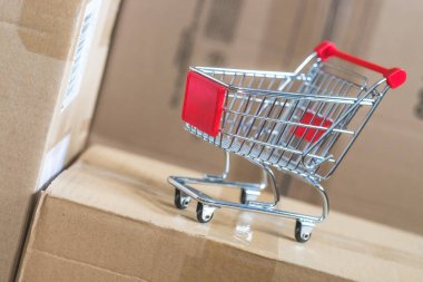 Online alışveriş ve parsel hizmet anlayışı: minyatür alışveriş sepeti ve karton kutular