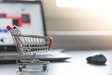 Online alışveriş kavramı: minyatür alışveriş sepeti, dizüstü bilgisayar ve fare bulanık arka planda