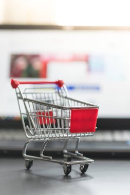Online alışveriş kavramı: minyatür alışveriş sepeti, dizüstü bilgisayar ve fare bulanık arka planda