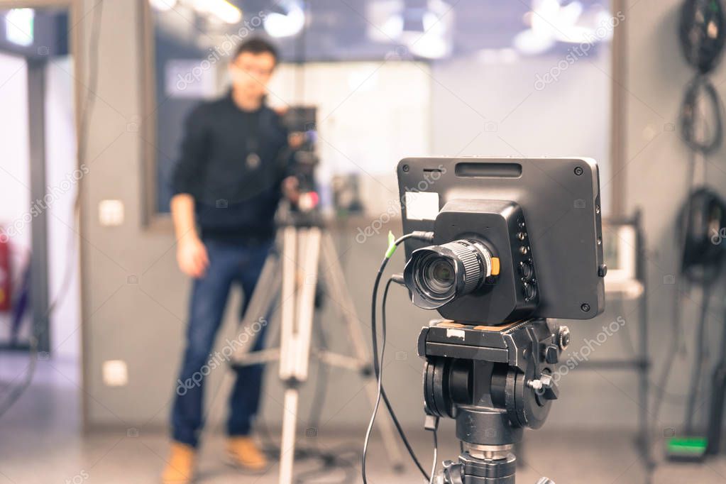 Film camera on a tripod in a television broadcasting studio, cameraman in the blurry background