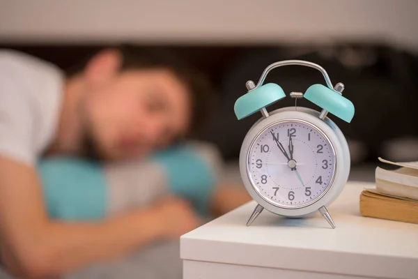 White Alarm Clock Bedside Table Young Man Sleeps Background — Stock Photo, Image