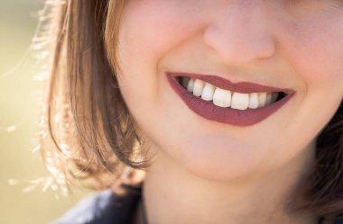 Kiraz kırmızı dudaklar ve beyaz dişler ile güzel kız gülümsüyor