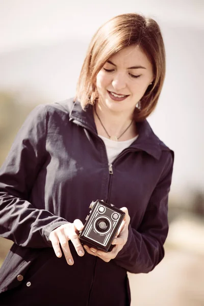 stock image Cute girl is making pictures with a vintage camera, outside