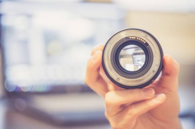 Genç fotoğrafçı bir fotoğraf lens, dizüstü bulanık arka planda bakıyor
