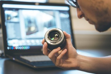 Genç fotoğrafçı bir fotoğraf lens, dizüstü bulanık arka planda bakıyor