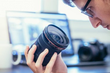 Genç fotoğrafçı bir fotoğraf lens, dizüstü bulanık arka planda bakıyor