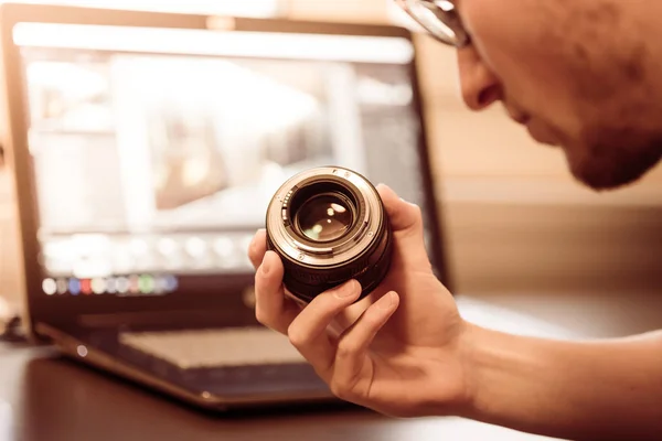 Ung Fotograf Tittar Ett Fotografi Objektiv Laptop Den Suddiga Bakgrunden — Stockfoto