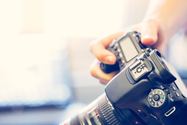 摄影师拿着一个专业的相机 手里拿着长焦镜头 笔记本电脑在模糊的背景下 — 图库照片