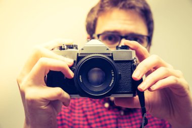 Kırmızı-mavi ekose desenli gömlek genç adam bir vintage fotoğraf makinesi, retro tarzı bir fotoğraf çekimi