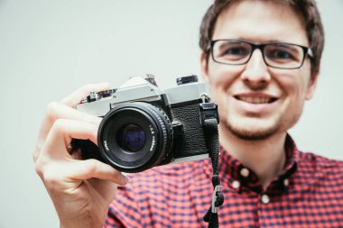 Kırmızı-mavi ekose desenli gömlek genç adam bir vintage fotoğraf makinesi, retro tarzı bir fotoğraf çekimi