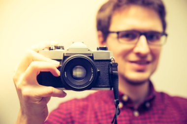 Kırmızı-mavi ekose desenli gömlek genç adam bir vintage fotoğraf makinesi, retro tarzı bir fotoğraf çekimi