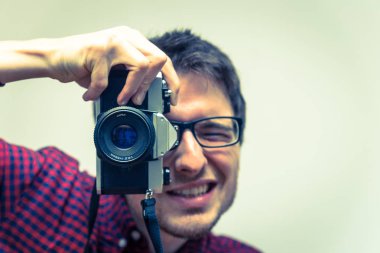 Kırmızı-mavi ekose desenli gömlek genç adam bir vintage fotoğraf makinesi, retro tarzı bir fotoğraf çekimi