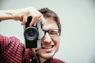 Kırmızı-mavi ekose desenli gömlek genç adam bir vintage fotoğraf makinesi, retro tarzı bir fotoğraf çekimi
