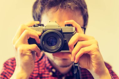 Kırmızı-mavi ekose desenli gömlek genç adam bir vintage fotoğraf makinesi, retro tarzı bir fotoğraf çekimi