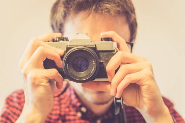 Kırmızı-mavi ekose desenli gömlek genç adam bir vintage fotoğraf makinesi, retro tarzı bir fotoğraf çekimi