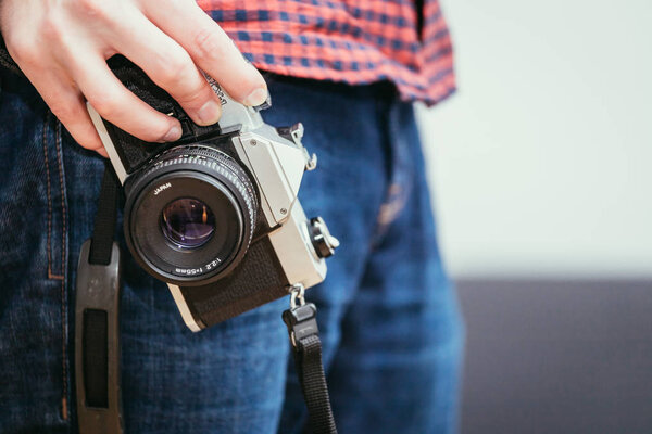Мужчина держит винтажную камеру в руке, джинсы и рубашку
