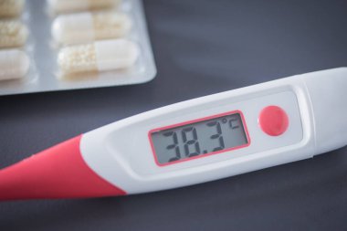 Kırmızı ateş termometre dijital gösterge ve masanın üzerinde yatan hapları ile