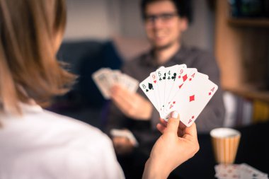 Kart evde oynamak: arkadaşlar bir masada oturuyor. Oyun kartları, dostum bulanık arka planda kadın.