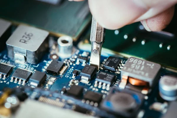 Technician is fixing a computer circuit board, hand and screwdri