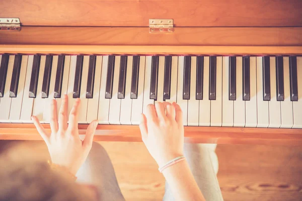Chica está tocando el piano en casa, vista de ángulo alto, fondo borroso — Foto de Stock