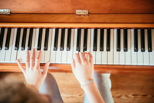 Chica está tocando el piano en casa, vista de ángulo alto, fondo borroso — Foto de Stock