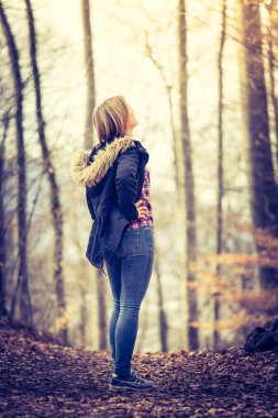 Sevimli genç kız mavi parker ile ormanda autu duruyor