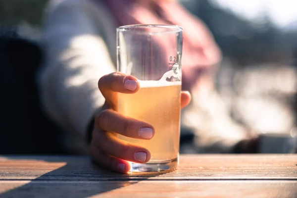 Woman with pink finger polish is drinking a glass of lemonade, o