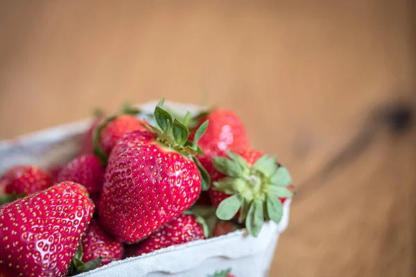 Léto: Čerstvé červené jahody v šálku, dřevěný stůl — Stock fotografie
