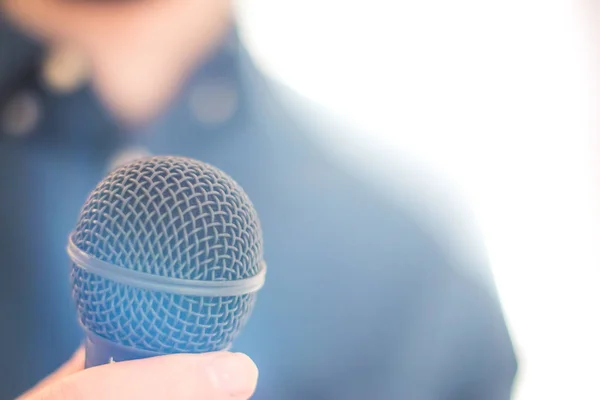 Journalist is holding a microphone in the foreground, blurry bac — Stock Photo, Image