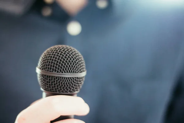 Journalist is holding a microphone in the foreground, blurry bac — Stock Photo, Image