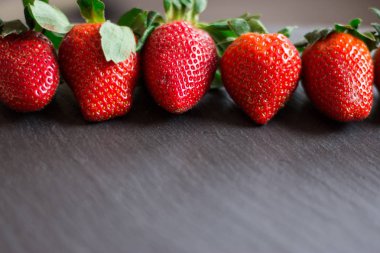 Fotoğrafı üzerinde siyah bir ston yalan taze kırmızı çilek kapatın