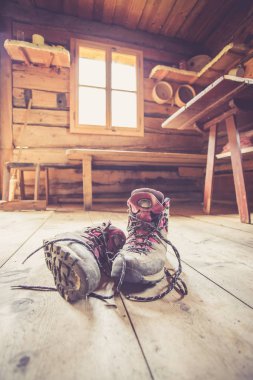 Alpine boots on rustic wood floor in an abandoned mountain chale clipart