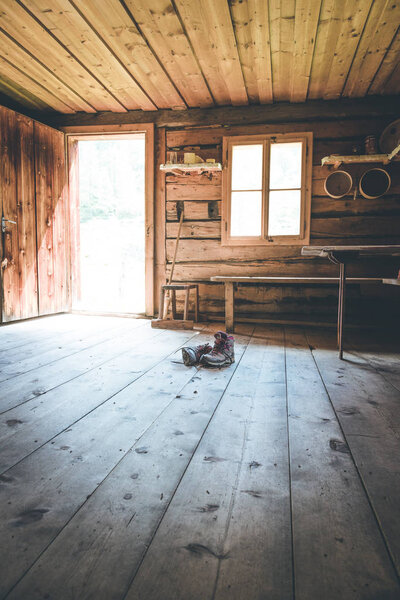 Alpine boots on rustic wood floor in an abandoned mountain chale