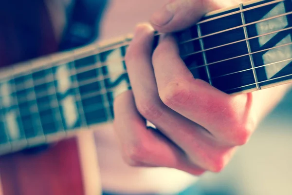 Recorte de un joven tocando una guitarra occidental sunburst — Foto de Stock