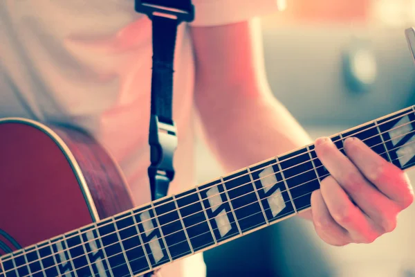 Recorte de un joven tocando una guitarra occidental sunburst — Foto de Stock