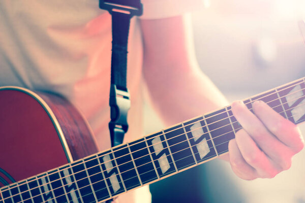 Cut-out of a young man playing a sunburst western guitar