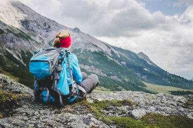 Dağcı sırt çantası ile taşlı yerde oturan bir