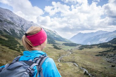 Kadın sarışın dağcı sırt çantası ile vie keyif alıyor