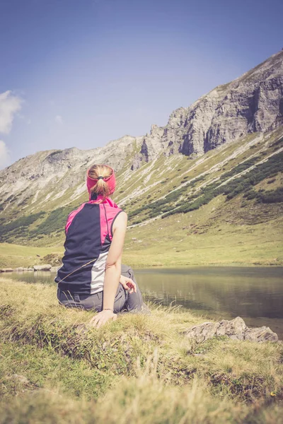 Mountain climber is sitting on the ground and doing a break duri — Stock Photo, Image