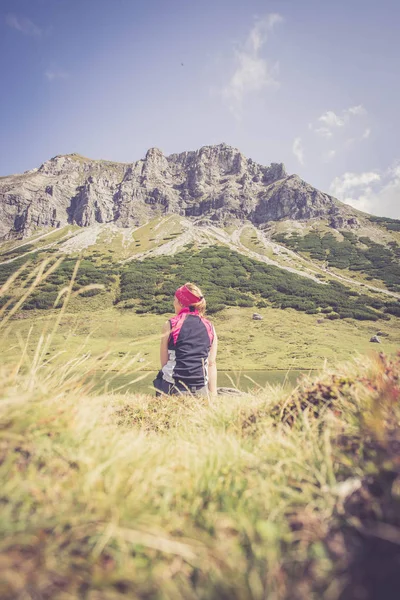 Mountain climber is sitting on the ground and doing a break duri — Stock Photo, Image