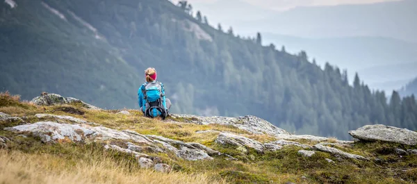 Bergbeklimmer met rugzak zit op de stenige grond een — Stockfoto