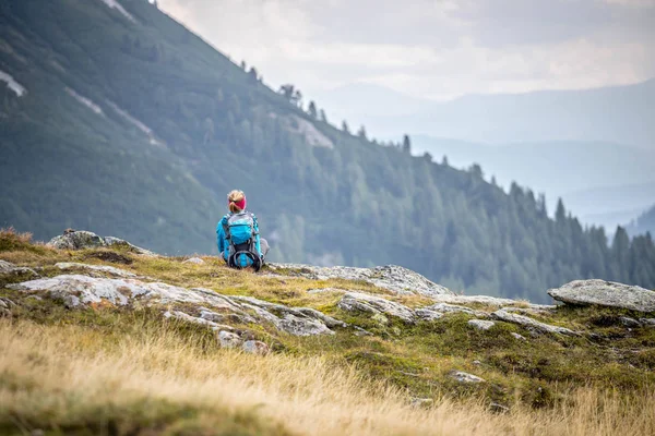 Альпинист с рюкзаком сидит на каменистой земле и — стоковое фото