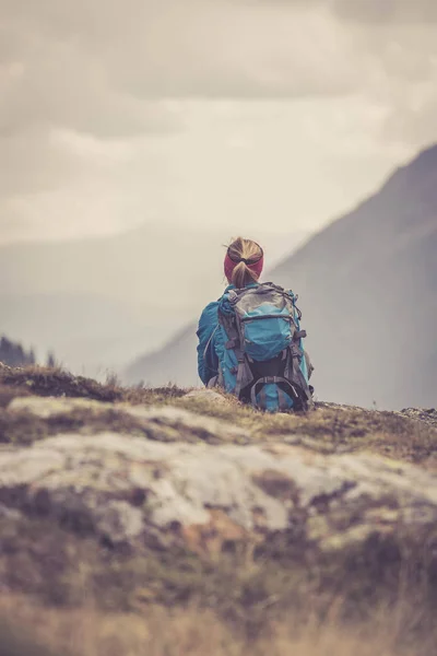 Альпинист с рюкзаком сидит на каменистой земле и — стоковое фото