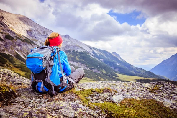 Montañista con mochila está sentado en el suelo pedregoso un — Foto de Stock