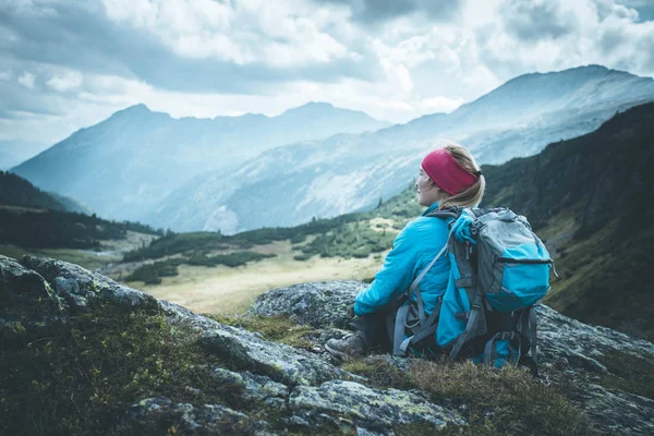 Mountain climber with backpack is sitting on the stony ground an — Stock Photo, Image