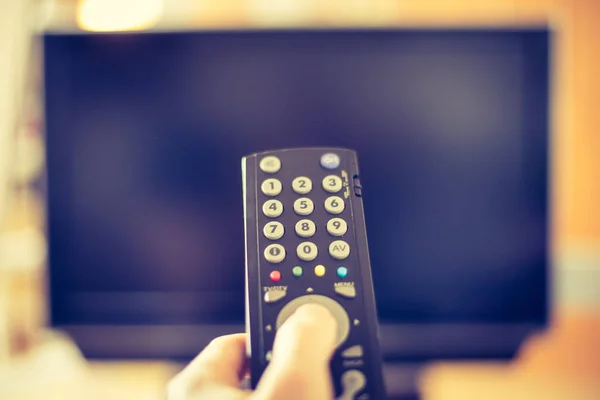 Male hand is holding TV remote control, smart TV.